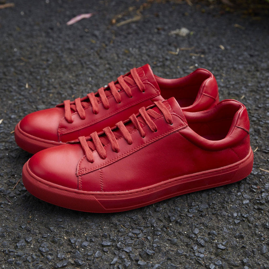 a pair of mens red dress sneakers on the pavement